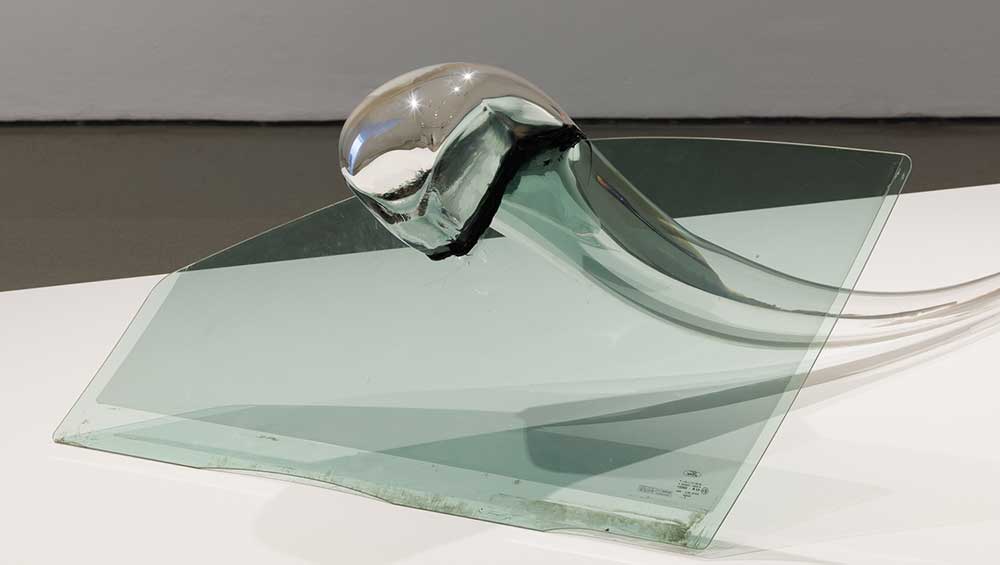 Petr Stanicky, Mirror-Mondeo Bite, 2014. Car window with blown and mirrored glass. Installation view of A State of Matter: Modern and Contemporary Glass Sculpture on display at the Henry Moore Institute 18 February - 5 June 2022. Photo: Rob Harris.