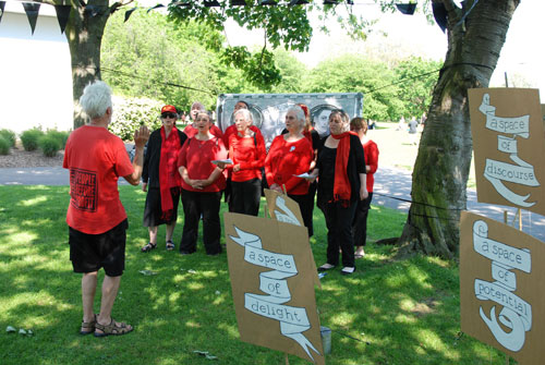 The Strawberry Thieves Choir, with placards, banner and bunting by Rachael House, 2012.