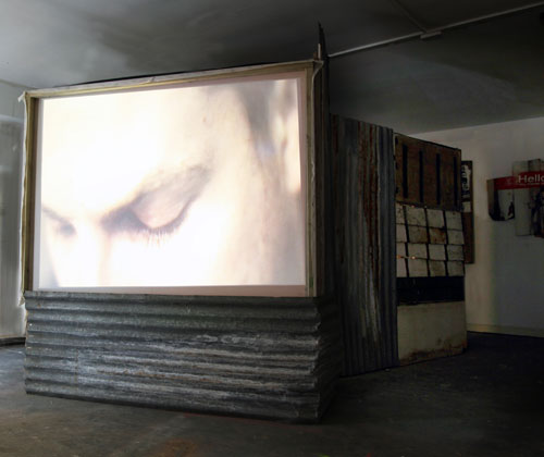 Giorgio Bruni. And What? (outer screen view), 2010. DVD loop, TVs, projection, wood, corrugated iron, dimensions variable. © the artist.