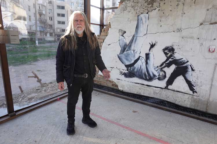 George Gittoes with mural by Banksy, Borodyanka, 2023.
