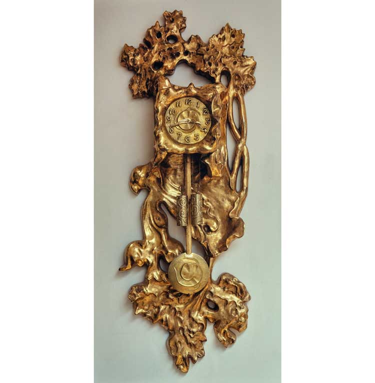 Clock for Casa Mila, 1905-1910. Workshop Esteva Figueras y Ses de Hoyos (manufacturer). Golden wood and brass, 103  ×  50  ×  20 cm. Collection Kiki et Pedro. Photo © Jacques Pepion / Sophie Crépy.