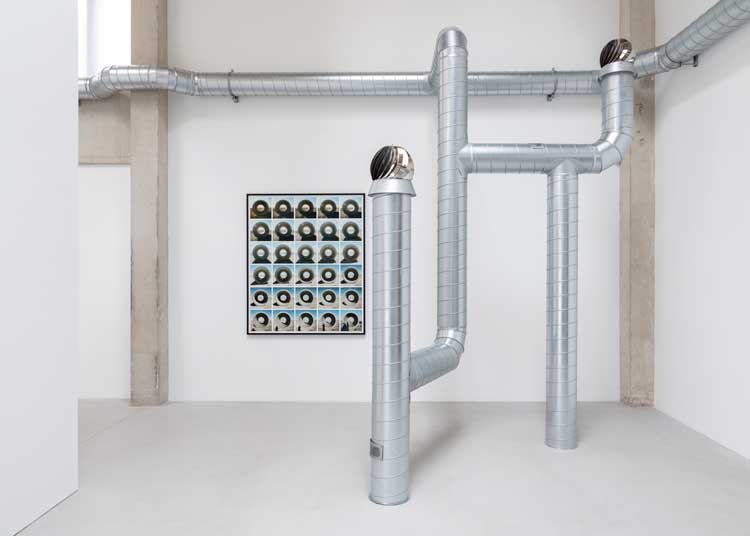 Nancy Holt, Sun Tunnels: Shifting Shadows, 1976, composite inkjet print on archival rag paper. Ventilation Systems, 1985-92 (detail), steel ducts, turbine ventilators, shanty caps, fans, air. Installation view, Nancy Holt, MoonSunStarEarthSkyWater, Goodwood Art Foundation, 2026. Artwork © Holt/Smithson Foundation / Licensed by Artists Rights Society, New York. Photo: Lucy Dawkins / Courtesy Goodwood Art Foundation.