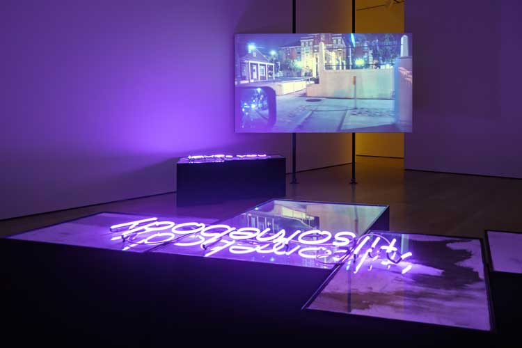 Freddy Villalobos, waiting for the stone to speak, for I know nothing of aventure, 2025. Single-channel video, automotive paint (Cadillac Black Rose and Cadillac Black Diamond), MDF, pigment suspended in slaked lime on burlap, acrylic sheet, neon, subwoofer, chopped and screwed audio, steel, lime plaster projection screen. Courtesy of the artist. Made in L.A. 2025, installation view, Hammer Museum, Los Angeles, October 5, 2025–March 1, 2026. Photo: Sarah Golonka.
