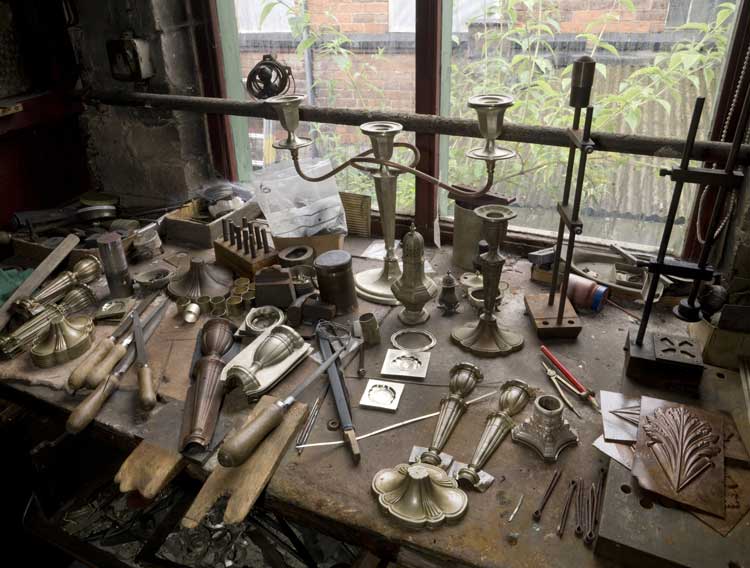 Finished candlesticks sit alongside moulds and tools. JW Evans produced a huge range of tableware, jewellery and other items, especially in the years leading up to the first world war. Image courtesy English Heritage.