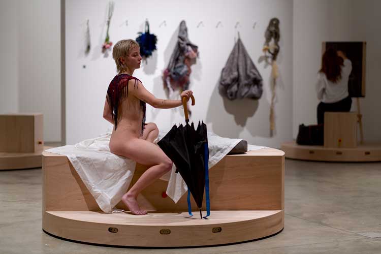 Laura Lima, The Drawing Drawing, 2026. Mechanised platforms (wood, metal, motors, electrical components, wheels), life model, paper, pencils and pens, still life display, ICA visitors. Installation view, Institute of Contemporary Arts, London. Photo: Anne Tetzlaff.