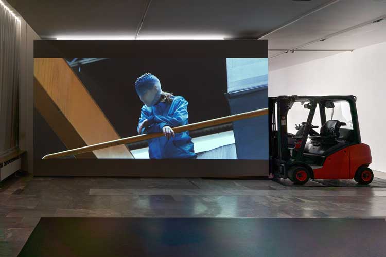 La Horde, Novaciéries, 2015. Single-channel video installation; projection wall, forklift, dance mats, video, 16′48′′, colour, sound. Dimensions variable. Installation view, (LA)HORDE, JSF Berlin. Photo: Alwin Lay.