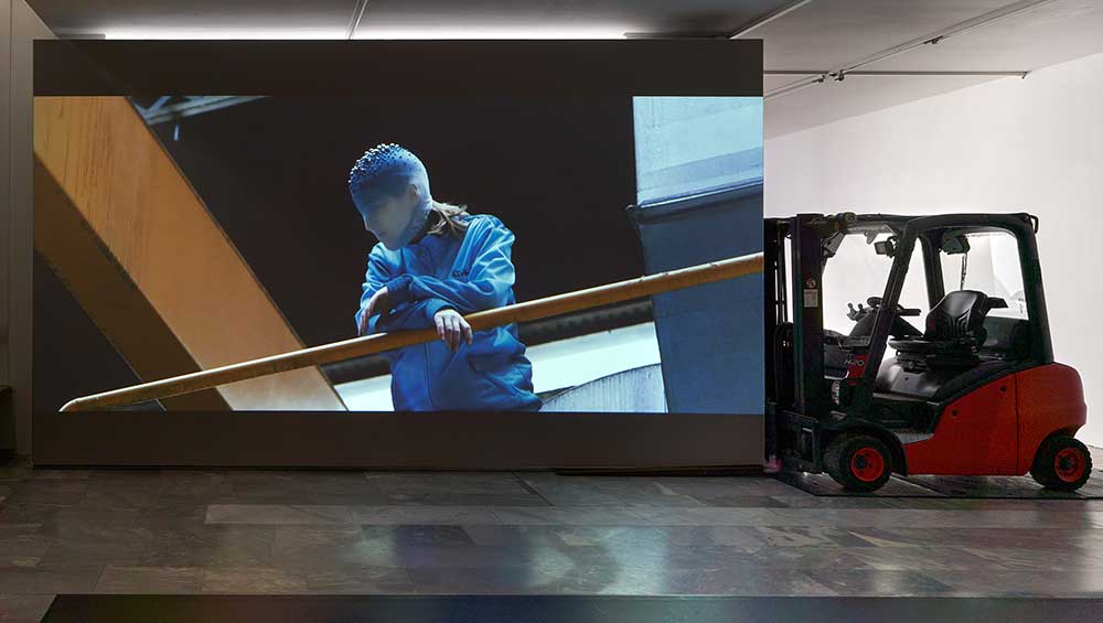 La Horde, Novaciéries, 2015. Single-channel video installation; projection wall, forklift, dance mats, video, 16′48′′, colour, sound. Dimensions variable. Installation view, (LA)HORDE, JSF Berlin. Photo: Alwin Lay.