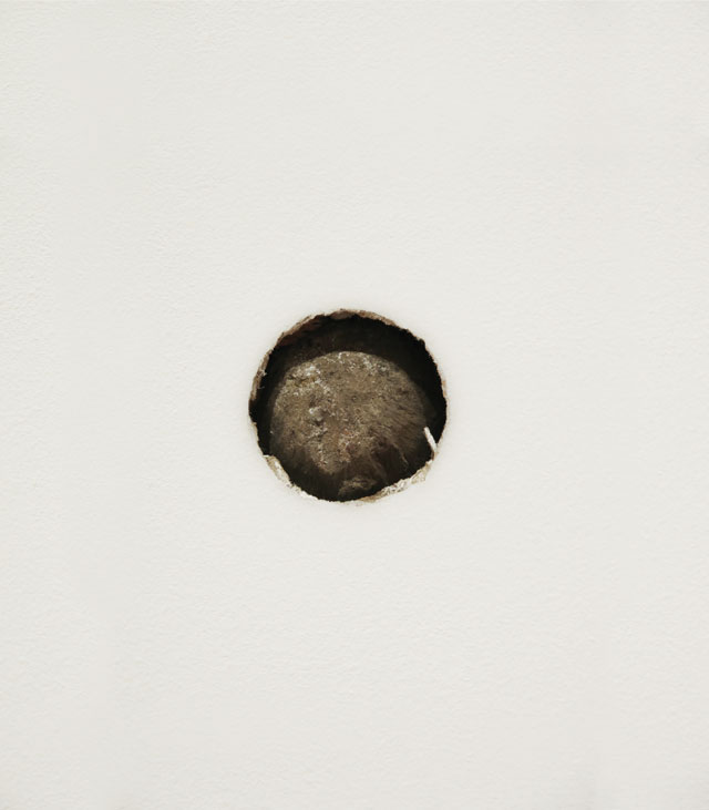 Peter Liversidge. Proposal for The Aldrich Museum No. 6: Re-enactment in the South Gallery of The Aldrich Museum of the Action that Caused a Cannonball to be Lodged in the North Façade of the Keeler Tavern, 2016. Three-pound lead cannonball, drywall, plywood, 2 1/2 x 2 1/2 x 3 1/2 in. © Peter Liversidge. Photograph: Tom Powel Imaging. Courtesy: Sean Kelly, New York.