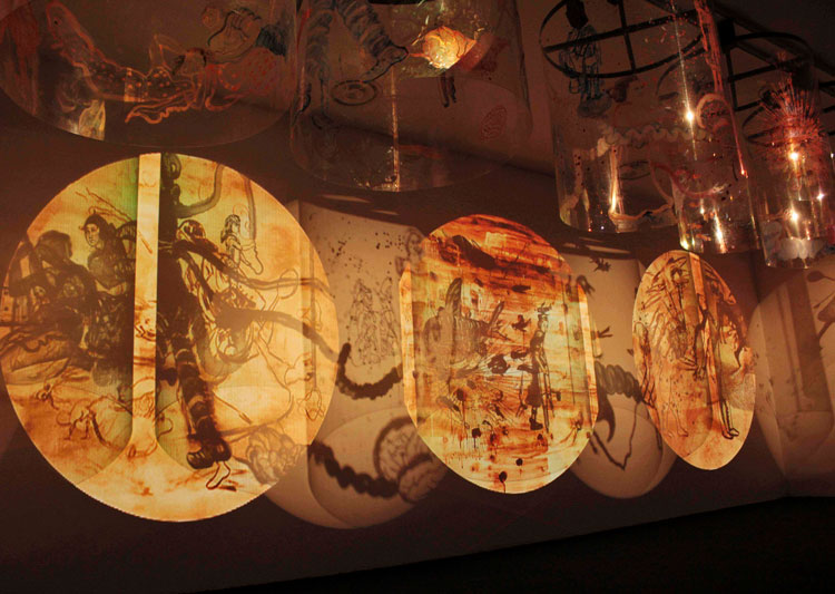 Nalini Malani, Remembering Mad Meg, 2007. Four channel video/shadow play, with eight reverse painted Lexan Cylinders, each 122 x 122 cm. Installation view: Paris-New Delhi-Bombay, Centre Pompidou, 2011. Collection: Centre Pompidou, 2011. Photo: Payal Kapadia. © Nalini Malani.