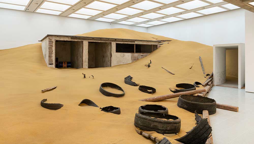 Installation view of Mike Nelson, Triple Bluff Canyon (the woodshed), 2004. Various materials. M25, 2023. Found tyres. Photo: Matt Greenwood. Courtesy the artist and the Hayward Gallery.