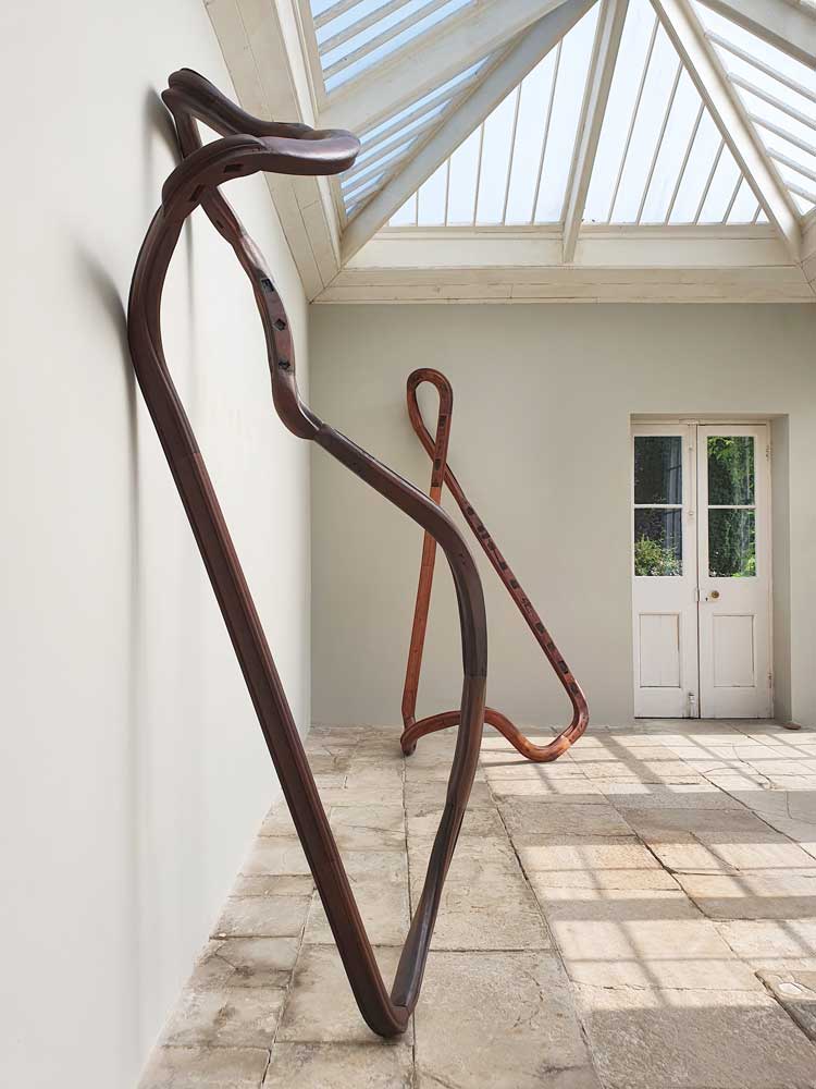 Nika Neelova. Foreground: Lemniscate XI/II, 2021. Hardwood reclaimed handrails, two flights of stairs, 280 x 130 x 60 cm. Background: Lemniscate IX, 2020. Hardwood reclaimed handrails, two flights of stairs, 310 x 130 x 70 cm. Installation view, One of Many Fragments, New Art Centre, Roche Court, Salisbury 2021.