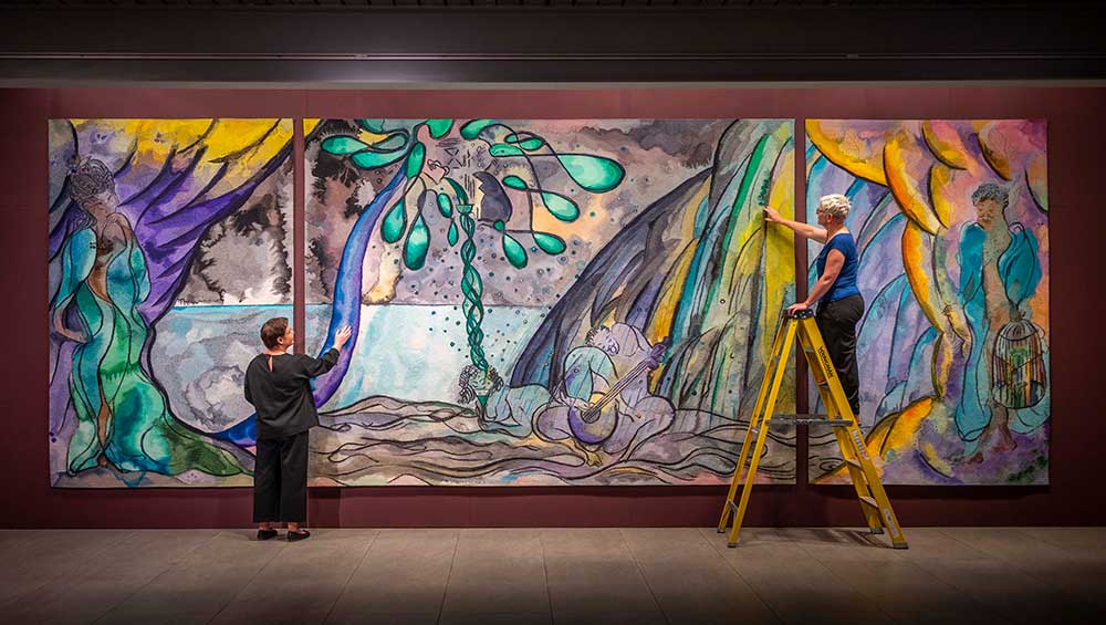 Installation view, Chris Ofili: The Caged Bird's Song, Dovecot Studios, Edinburgh, 2024 featuring The Caged Bird's Song tapestry triptych by Chris Ofili, 2014–2017. © The artist. Courtesy the artist and Victoria Miro, The Clothworkers' Company and Dovecot Tapestry Studio, Edinburgh. Photo: Phil Wilkinson.