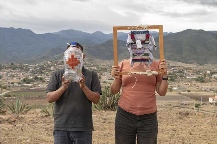 Fowler Museum at UCLA in partnership with the Museum of Contemporary Art Santa Barbara. Sangre de Nopal/Blood of the Nopal: Tanya Aguiñiga and Porfirio Gutiérrez in Conversation.
Artists Porfirio Gutiérrez and Tanya Aguiñiga hold their weavings in front of their faces on a hill near Gutiérrez’s hometown in Teotítlan del Valle, Oaxaca. Photo: Javier Lazo Gutiérrez.