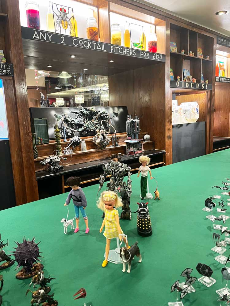 An unusual dog walk on the Wetherspoon's bar, with home brew bottles among the offerings at the back. Installation view, Come As You Really Are by Hetain Patel and Artangel, Grants, Croydon 2024. Photo: Veronica Simpson.