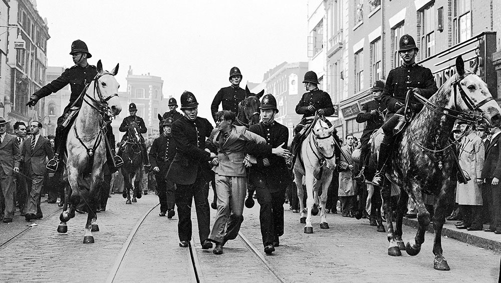 Eddie Worth. An anti-fascist demonstrator is taken away under arrest after a mounted baton charge during the Battle of Cable Street, London, 4 October 1936. © Alamy.