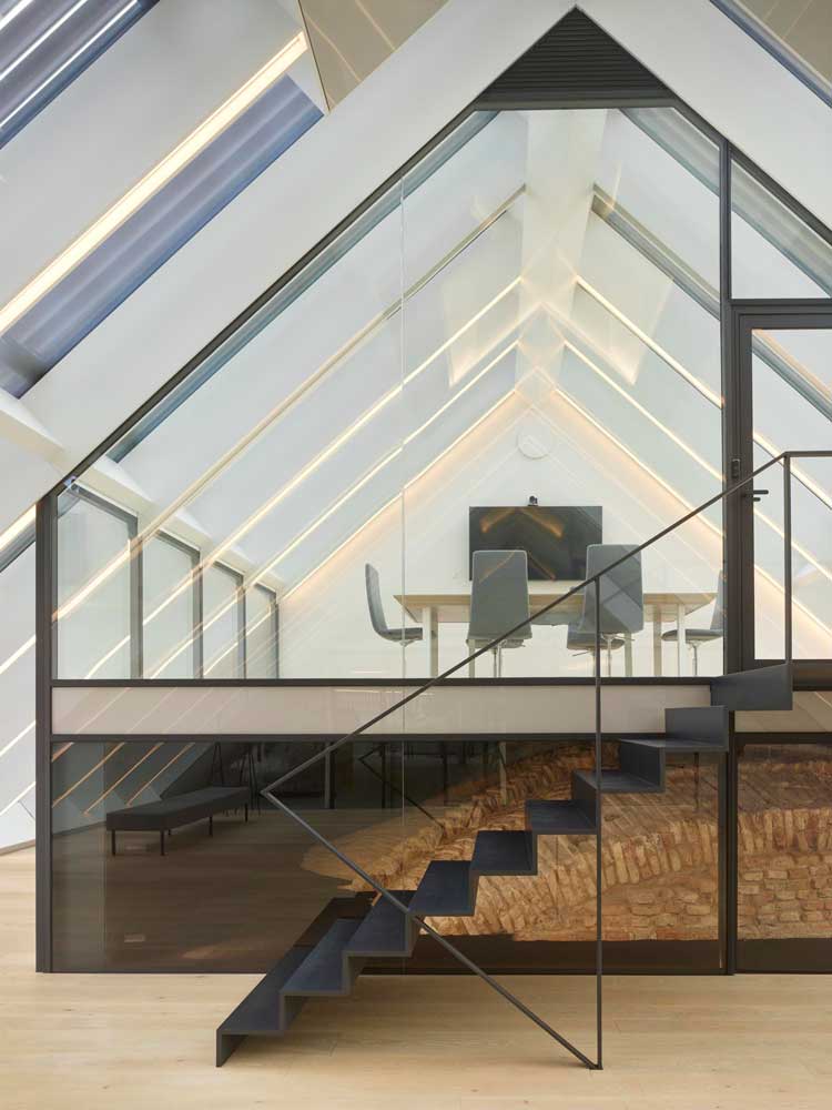 Boksto 6, Vilnius, Lithuania, 2020. A top floor office space. Seilern persuaded the planning office that windows could be incorporated into a smooth roofline, with a metal protective grille unifying the roofscape.