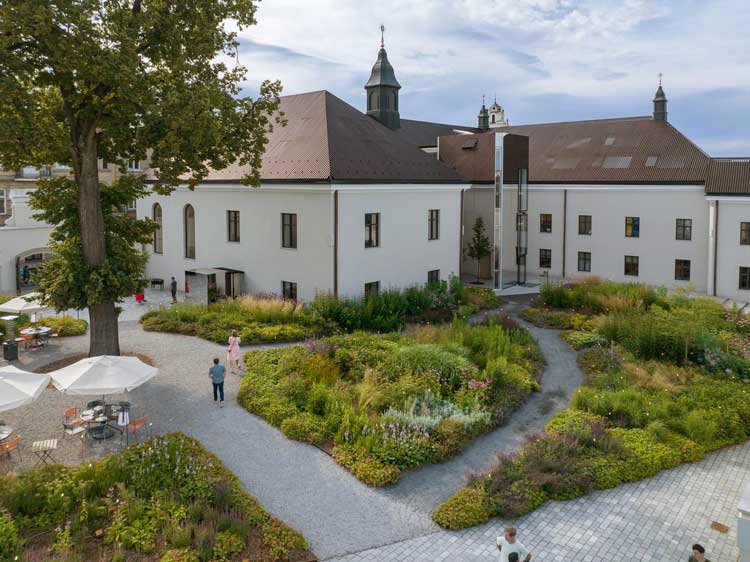 Boksto 6, Vilnius, Lithuania, 2020. The gardens are open access to the public, and the far building houses high quality office space from ground level, while below ground in the medieval vaults is a luxury spa. The chapel, on the left, is now an event space.