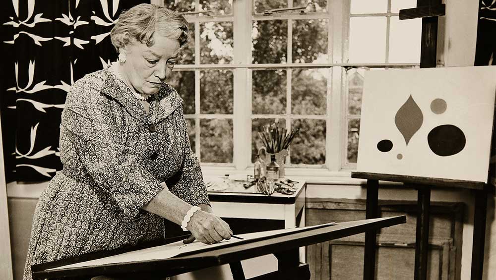 Paule Vézelay in her London studio with her 1955 textile Harmony (left) and her 1956 painting The Yellow Circle (right). Photograph, Estate of Paule Vézelay.